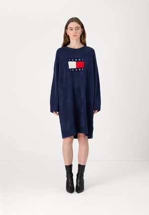 Abito maglione oversize blu navy realizzato in morbido tessuto a maglia; presenta una toppa con logo e accenti rosso e bianco sul davanti. Maniche lunghe.
