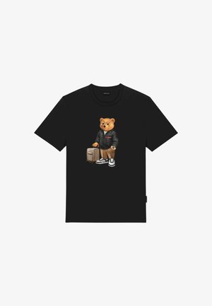 Maglietta nera con una grafica di un orso che indossa una giacca nera, orologio, sneakers e trascina una valigia beige con ruote.