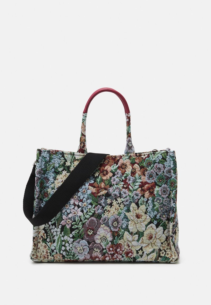 Sac fourre-tout en tapisserie florale avec deux petites poignées et une longue bandoulière noire réglable sur fond blanc.
