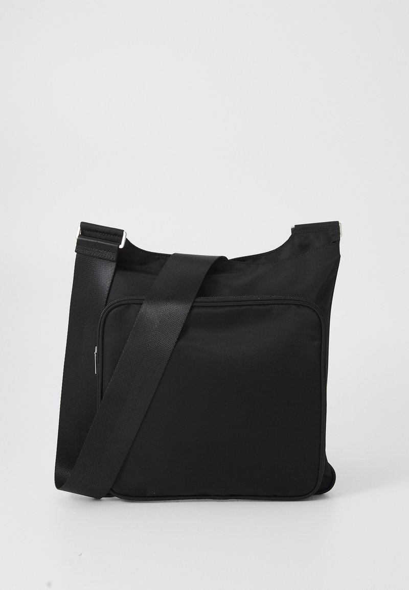 Borsa a tracolla nera realizzata in tessuto liscio, dotata di una larga tracolla regolabile, una tasca frontale con zip e un design minimalista.