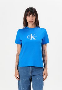 Tricou din bumbac albastru cu mânecă scurtă, av�ând un logo alb Calvin Klein la centru. Decupaj clasic la gât, croială lejeră, textură fină.