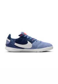 Nike tornacipő, világoskék és tengerészkék anyagok keverékével, fehér pipa logóval, texturált velúrral és mintás gumitalppal.