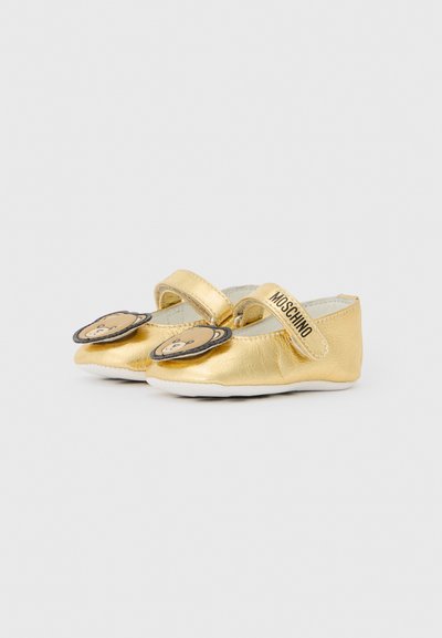 Bailarinas de cuero dorado con puntera redondeada, tira de Velcro y adornos de cara de oso en la puntera. Textura suave y suela flexible.