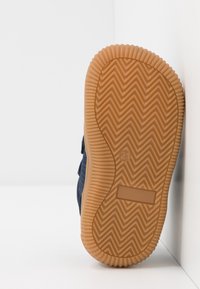 Námorníky tenisky s texturovaným textilním svrškem a gumovou podešví se zigzagovým vzorem. Vystužená špička a zapínání na suchý zip.