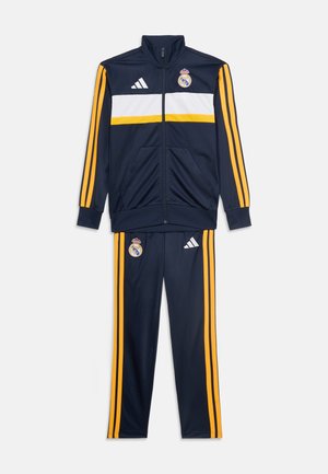 Granatowy sportowy dres z żółtymi paskami, białym poziomym pasem na kurtce, logo Real Madrid i Adidas na kurtce i spodniach.