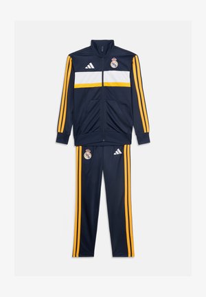 Granatowy sportowy dres z żółtymi paskami, białym poziomym pasem na kurtce, logo Real Madrid i Adidas na kurtce i spodniach.