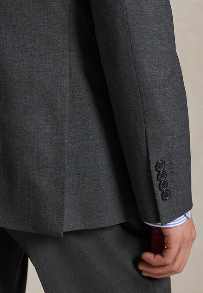Σκούρο γκρι σακάκι κοστουμιού με απαλό ύφασμα, δομημένο σχέδιο, λεπτομερή ραφές και τέσσερα μαύρα κουμπιά  στο μανίκι.
