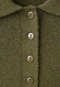 Cárdigan de punto color verde oliva con cuello, con seis botones redondos y de color claro a lo largo de la tapeta frontal. Textura suave.