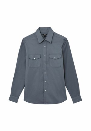 Harmaa pitkähihainen nappipaita, jossa on terävä kaulus, kaksi nappilistallista etutaskua ja napit hihansuissa.