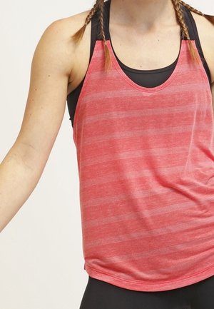 Frau trägt ein ärmelloses rotes gestreiftes Tanktop über einem schwarzen Sport-BH mit geflochtenem Haar, beschnitten an Schultern und Taille.