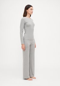 Ensemble comprenant un haut à manches longues gris côtelé et un pantalon ample, fabriqué dans un tissu doux, avec une silhouette ajustée et un motif texturé subtil.