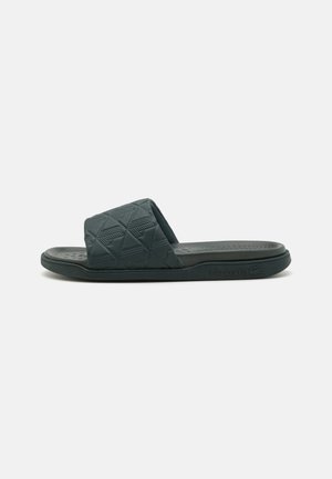Grijze rubberen slip-on sandaal met een gestructureerd kruispatroon op de band; platte zool en logo in de zijkant gedrukt.