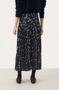 Jupe plissée mi-mollet en tissu bleu marine avec des motifs abstraits dorés et argentés. Elle dispose d'une taille élastique et d'un collant noir assorti.