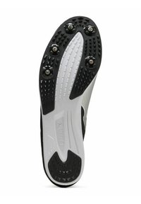 Zwart-witte atletische schoenzool met zes metalen spikes, gestructureerd rubber voor grip en een gebogen hakontwerp met contrasterende witte accenten.