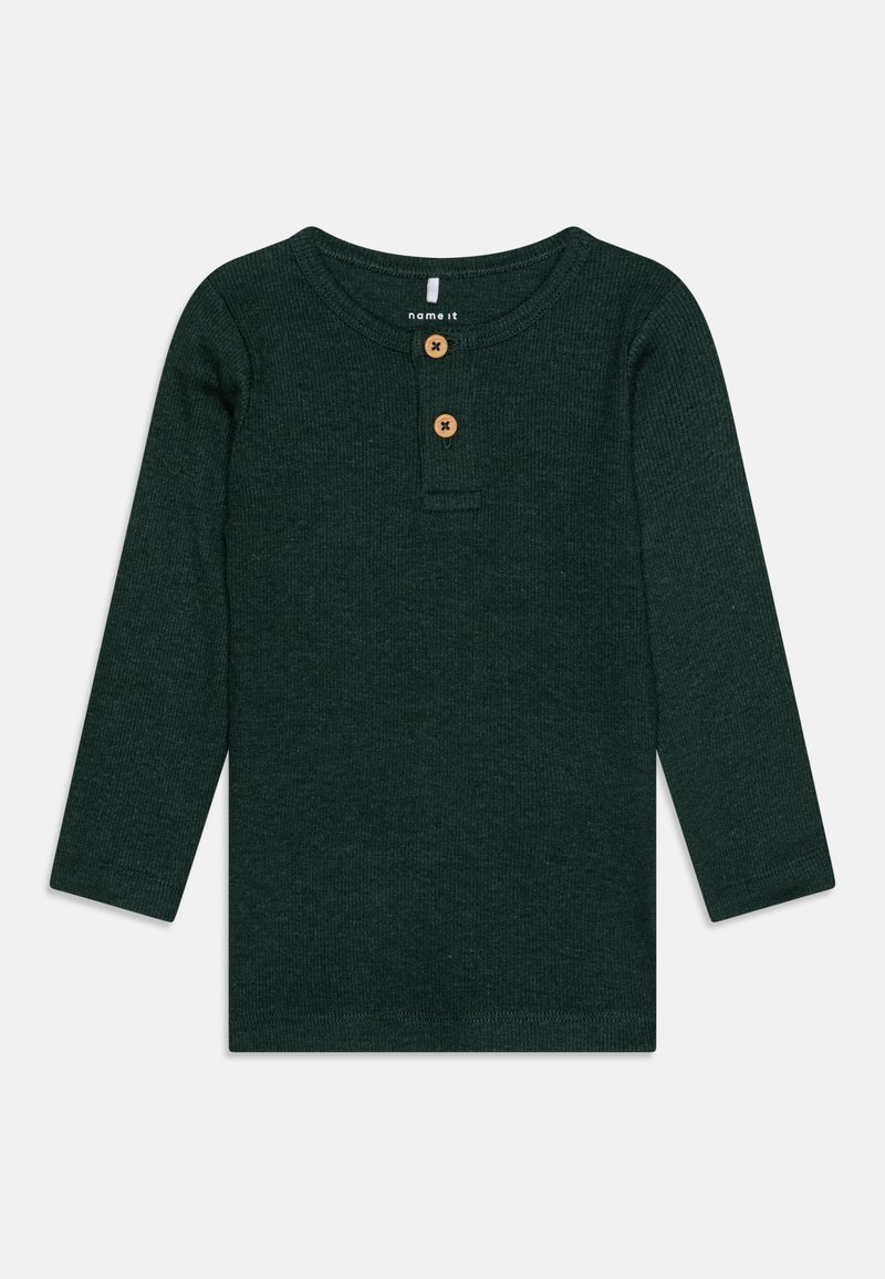 Mørkegrønn langermet ribbestrikket topp med rund hals, med tre treknapper ved nakken og rett fald. Myk stofftekstur.