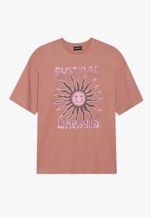 Ροζ T-shirt φτιαγμένο από βαμβάκι. Διαθέτει μια μεγάλη γραφική παράσταση ενός ήλιου με χαμογελαστό πρόσωπο και το κείμενο "ΜΥΣΤΙΚΑ ΟΝΕΙΡΑ" σε ροζ.
