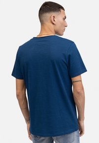 Camiseta de algodón azul marino con mangas cortas, escote redondo y corte relajado. La vista trasera muestra una textura suave y detalles de costura sutiles.