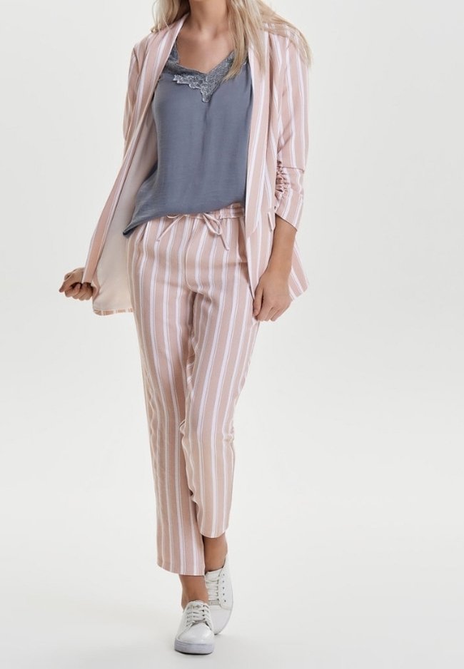 Jasnoróżowy i biały w paski garnitur z długim żakietem, w połączeniu z szarym topem bez rękawów i białymi trampkami. Materiał poliestrowy o gładkiej fakturze.