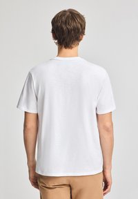 Vit kortärmad t-shirt med rund halsringning, tillverkad av mjukt bomullstyg. Enkel design utan mönster eller iögonfallande detaljer.