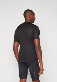 Melnas īsām piedurknēm sporta krekls ar teksturētu audumu, pieguļošu dizainu un muguras sieta paneļa. Melni šorti ar sānu kabatām un kontrastējošiem akcentiem.