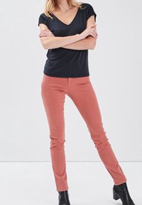 Top negro de manga corta con escote en V y hombros texturizados, combinado con pantalones rosas ajustados y botines negros.