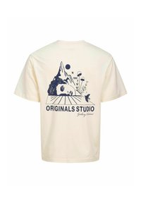 Krémszínű pamut póló, kék grafikai dizájnnal, amely hegyeket, egy arcot, növényeket és a "ORIGINALS STUDIO" és "1990" feliratokat ábrázol.
