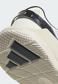 Sole di scarpa sportiva bianca con un design testurizzato, dettagli in gomma nera e testo "LIGHTSTRIKE 2.0" vicino al tallone.