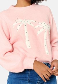 Pull en maille rose doux avec un col rond, arborant des palmiers blancs et des ornements de petites perles argentées. Poignets et ourlet côtelés.