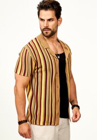 Kurzärmliges, knöpfbares Hemd in gelb-braun mit vertikalen Streifen in rot, marineblau und creme. Verfügt über einen Kragen und strukturierten Stoff.