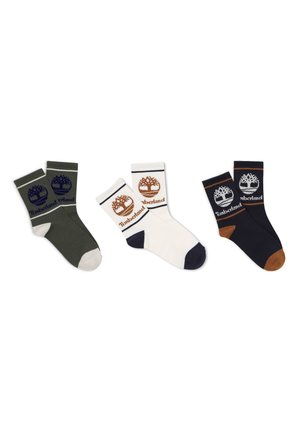 Trois paires de chaussettes Timberland vertes, blanches et noires, chacune arborant le logo de l’arbre Timberland et le nom de la marque sur le bord-côte.