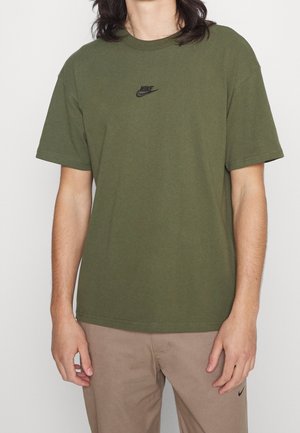 Olivgrünes Baumwoll-T-Shirt mit rundem Ausschnitt und kurzen Ärmeln, mit einem kleinen schwarzen Nike-Logo auf der linken Brust.