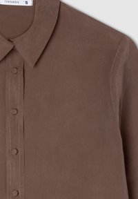 Camicia marrone con colletto, dalla texture liscia, con chiusura frontale a bottoni e bottoni coordinati, con cuciture sottili lungo la pattina.