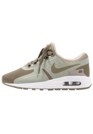 Zijaanzicht van een beige en lichtgroene Nike Air sneaker met mesh- en synthetische bovenkant, witte tussenzool en zichtbare luchtdemping in de hiel.