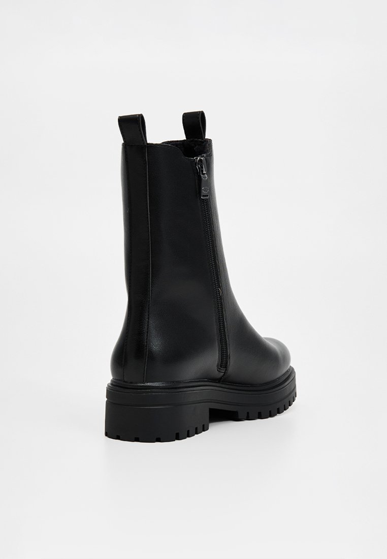 Bottes chevilles en cuir noir avec une fermeture éclair sur le côté, surface texturée, et une semelle en caoutchouc épaisse avec des détails de crantage.
