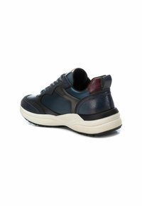 Zapatillas que combinan cuero azul oscuro y materiales textiles, acentos traseros texturizados, cordones redondos y una suela gruesa blanca.