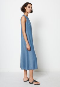 Uten ermer denimkjole i lys blå, med en avslappet passform og lengde til midten av leggen. Glatt tekstur med en rett nederkant.