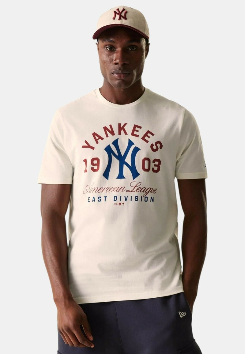 Camiseta de color crema con un logo de los Yankees en azul y texto en rojo. Con mangas cortas, cuello redondo y una textura de algodón suave.
