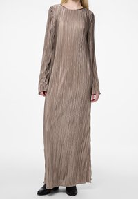 Robe longue plissée dans une couleur beige neutre avec des manches longues et un décolleté bateau. Le tissu texturé et les fentes latérales améliorent le mouvement.