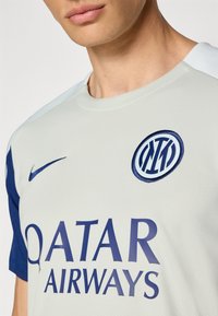 Nike football jersey in light grey with dark blue short sleeves. Features a prominent blue club logo and large text "Qatar Airways" on the front.