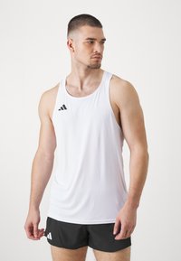 Hvid atletisk tanktop med sort Adidas-logo på øverste venstre side, som har et glat stof og ærmeløst design. Sammen med sorte shorts.