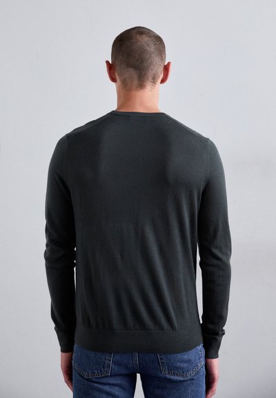 Dunkelgrauer Strickpullover, lange Ärmel, Rundhalsausschnitt, figurbetontes Design, glatte Textur, minimale Details, getragen mit blauen Jeans.