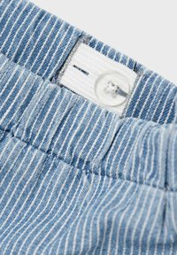 Fascia in tessuto a righe blu chiaro con un elastico bianco e un dettaglio a bottone trasparente visibile nella parte superiore.