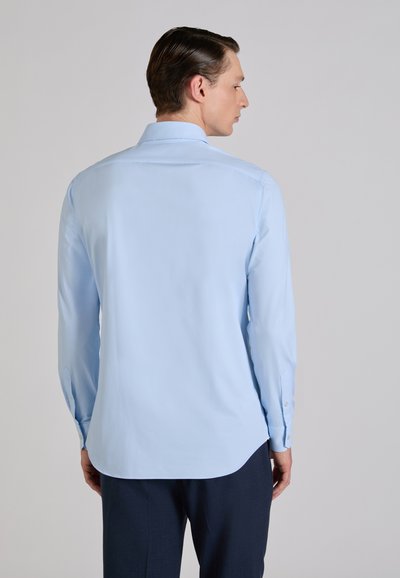 Camisa de manga larga azul claro con dobladillo recto y puños abotonados, hecha de tela suave, que presenta un diseño entallado en la espalda.