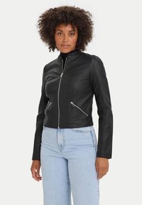 Giacca di pelle nera con zip frontale, design aderente, colletto alto e due tasche con zip; texture liscia con dettagli di cucitura sottili.