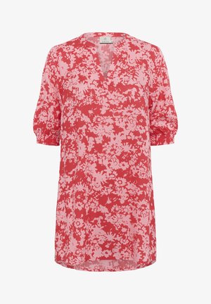 Punane lilleline tunika, millel on V-kaelus ja lühikesed puffvarrukad. Valmistatud kergest kangast, millel on roosa lillemuster punasel taustal.