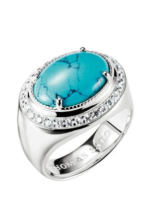 Silberner Ring mit großem ovalem Türkisstein in der Mitte, umgeben von kleinen klaren Kristallen in einer runden Fassung.