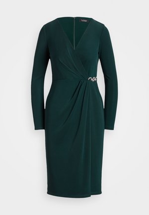 Vestido largo hasta la rodilla de manga larga y verde oscuro, con escote en V estilo cruzado y un broche decorativo plateado en la cintura del lado derecho.