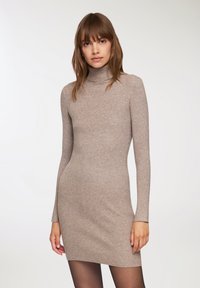 Vestito a collo alto beige a costine con maniche lunghe e silhouette aderente, realizzato in un tessuto morbido e elasticizzato.
