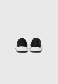 Black athletic shoes with a textured upper, white midsole, and black outsole, featuring a minimalist design and no visible branding.