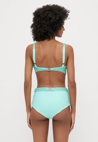 Turquoise bikini set featuring a textured glitter band, adjustable straps, and high-waisted bottom with a smooth finish.